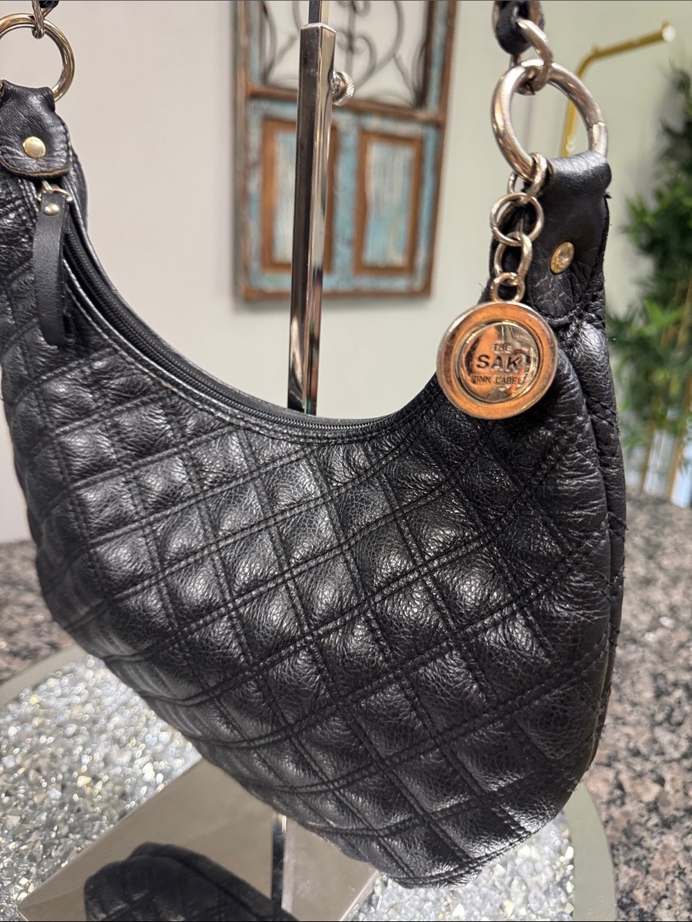The Sak Black Quilted Leather Shoulder Bag with Brass Medallion chain strap